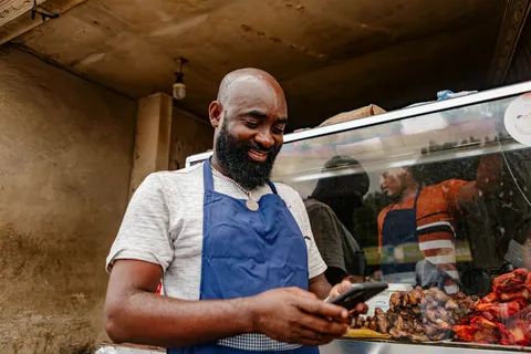A small business owner in an apron checking his phone at work